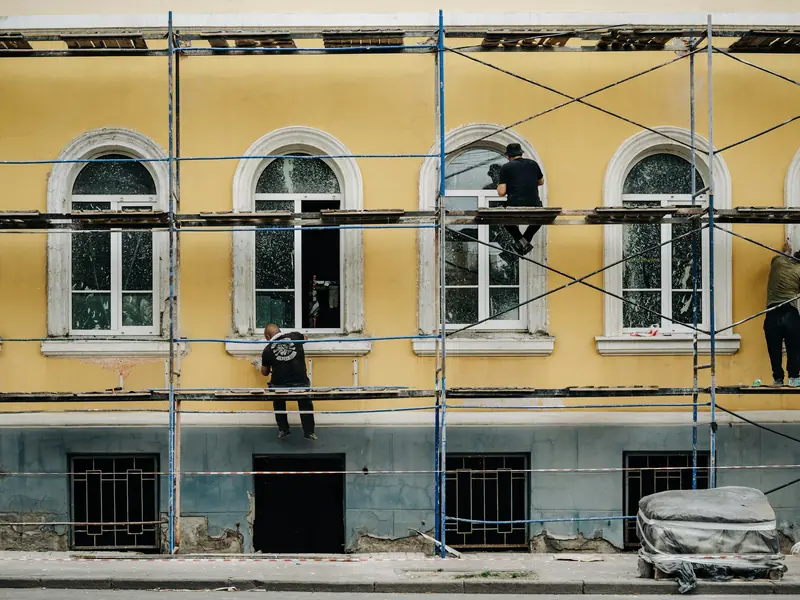 Ouvriers sur un échafaudage le long d'une façade jaune en réfection