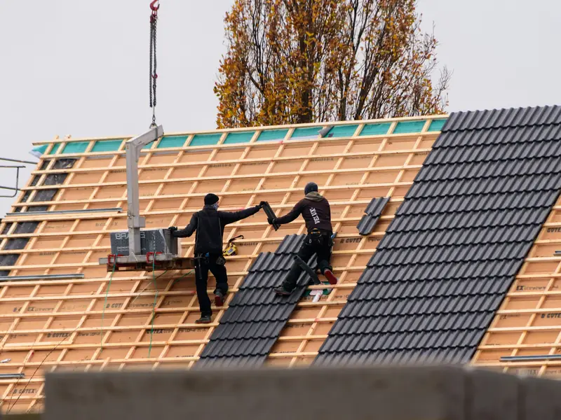Couvreurs posant des tuiles neuves sur des liteaux